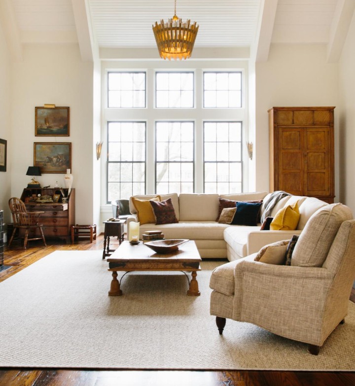 A living room with a biege rug and sofa set.