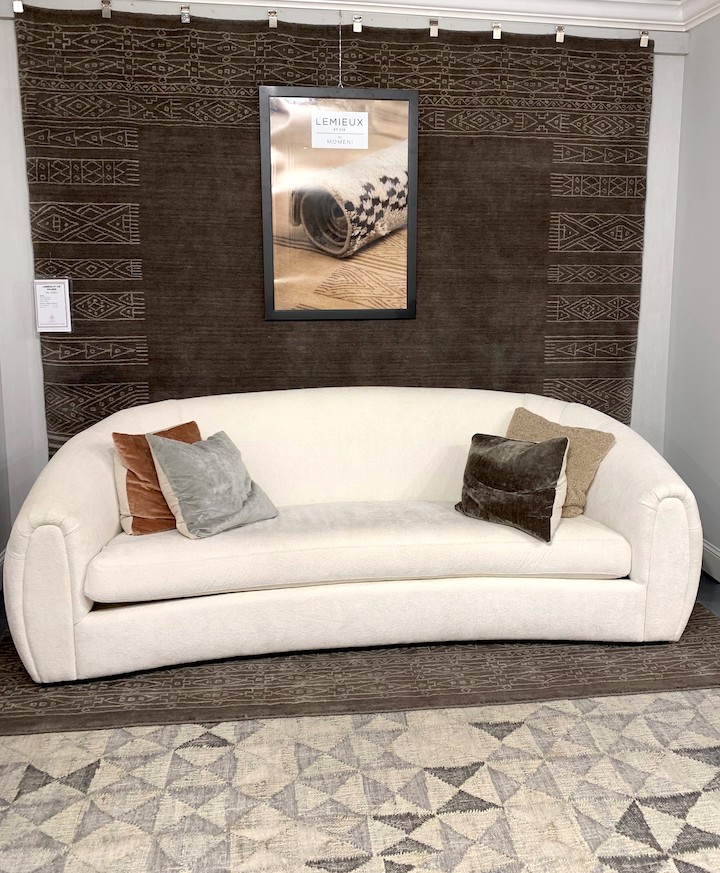 two tribal design rugs with a curved ivory sofa in showroom display