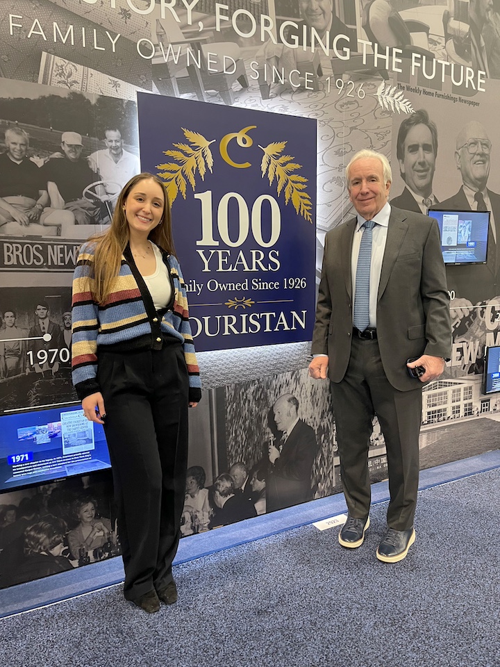 George and Georgia Couri in front of Couristan's history wall at TISE