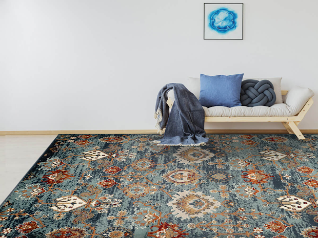 A white couch with blue pillows on a blue rug with an intricate design of cream