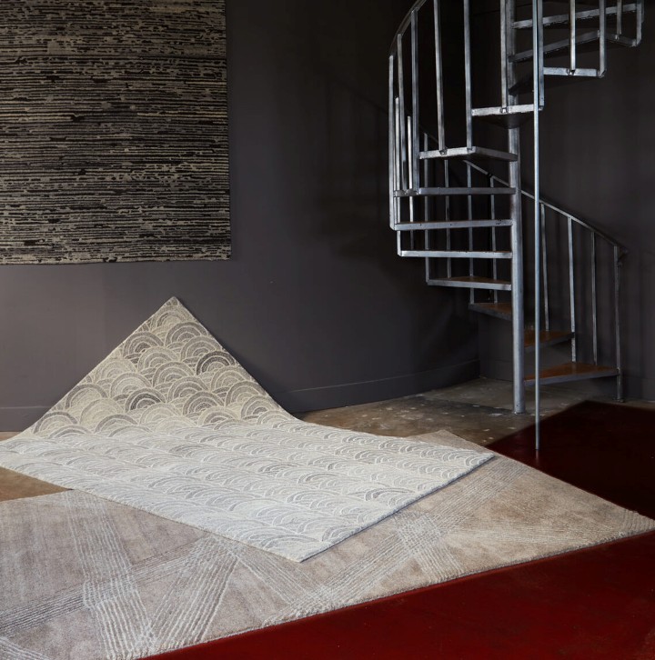 Three rugs draped on top of each other, in font of a spiral staircase