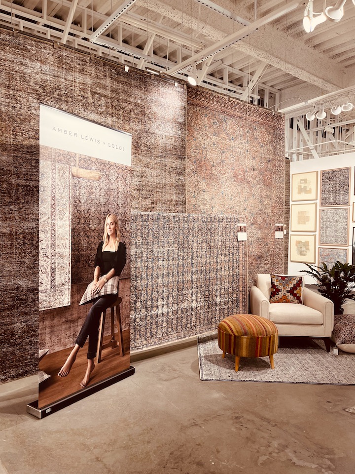 poster of designer Amber Lewis by a display of her new Loloi area rugs