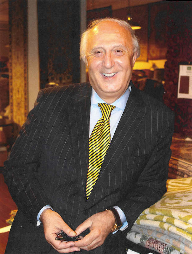 portrait of David Harounian leaning on a stack of rugs